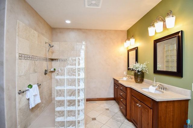 bathroom with a tile shower, tile patterned flooring, and vanity