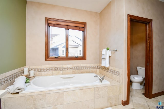 bathroom with tile patterned floors, toilet, and tiled bath