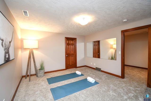 exercise room featuring carpet floors and a textured ceiling