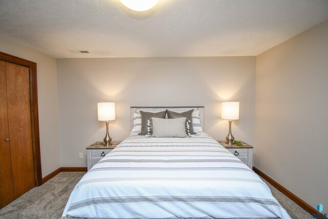 carpeted bedroom featuring a textured ceiling and a closet