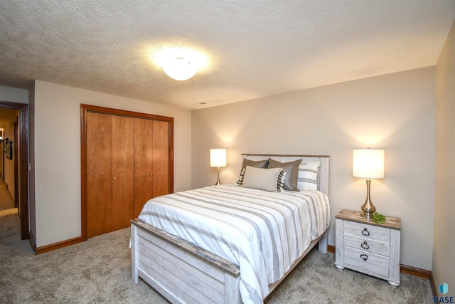 bedroom with light carpet, a textured ceiling, and a closet