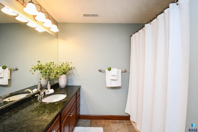 bathroom featuring tile patterned floors, vanity, and a textured ceiling