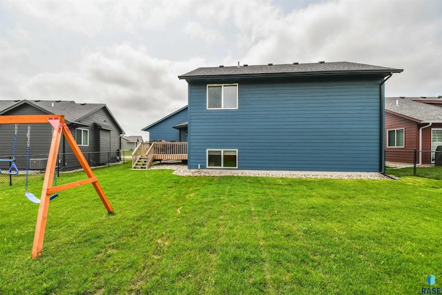 rear view of property with a playground, a yard, and a wooden deck