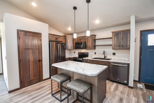 kitchen featuring sink, hanging light fixtures, vaulted ceiling, a kitchen island, and appliances with stainless steel finishes