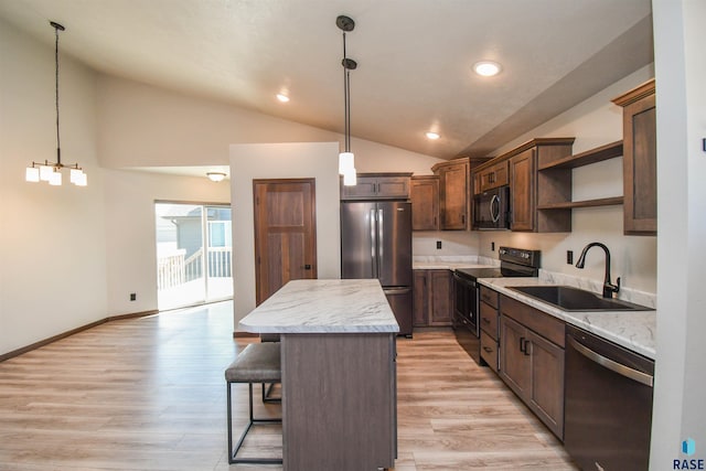 kitchen featuring pendant lighting, black appliances, sink, vaulted ceiling, and a kitchen island