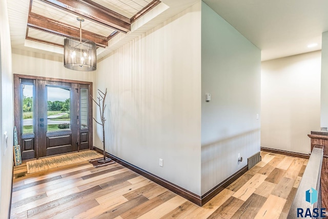 foyer with light hardwood / wood-style flooring, beamed ceiling, and an inviting chandelier