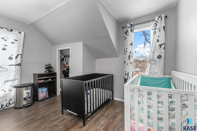 bedroom with dark hardwood / wood-style floors, lofted ceiling, a textured ceiling, and a nursery area