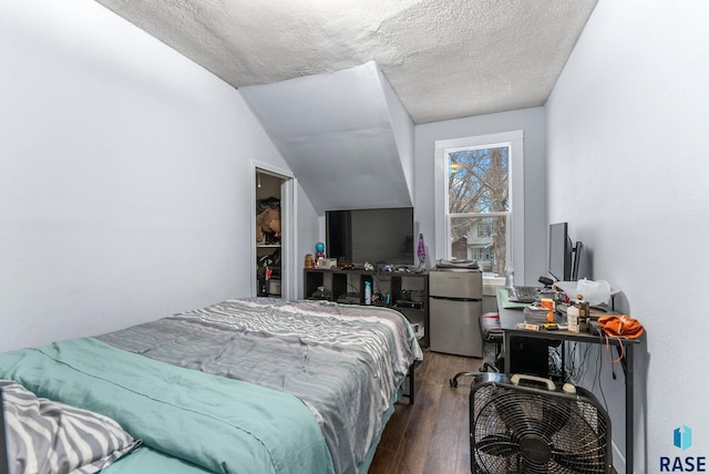 bedroom featuring stainless steel fridge, a textured ceiling, vaulted ceiling, and dark wood-type flooring