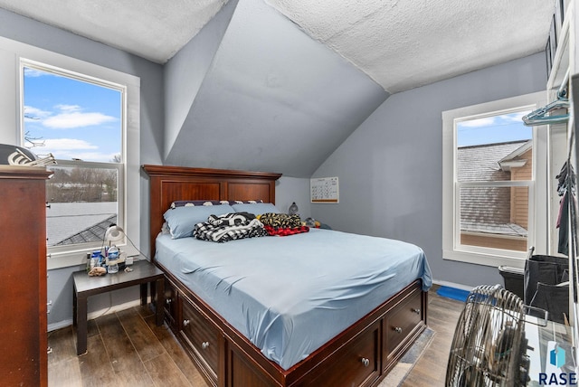 bedroom featuring a textured ceiling, multiple windows, hardwood / wood-style floors, and vaulted ceiling