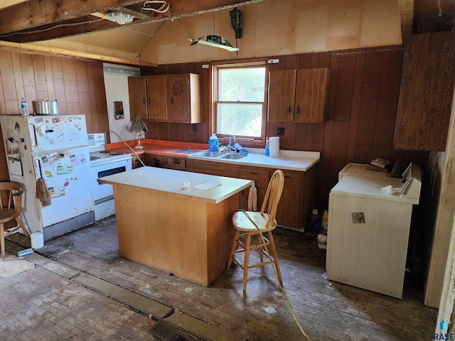 kitchen with white appliances, sink, separate washer and dryer, a center island, and wood walls