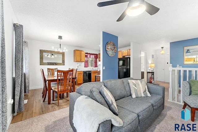 living room featuring a textured ceiling, light hardwood / wood-style floors, and ceiling fan with notable chandelier