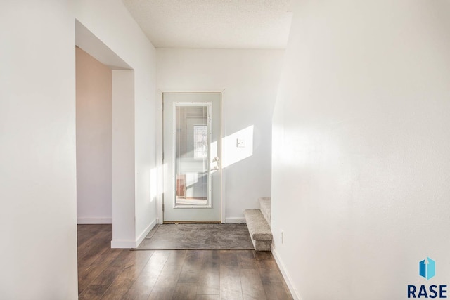 doorway to outside featuring dark wood-type flooring and a textured ceiling