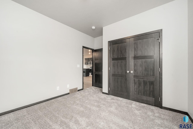 unfurnished bedroom with a closet and light colored carpet