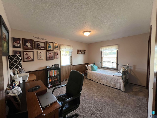 bedroom with multiple windows, wooden walls, carpet floors, and a textured ceiling