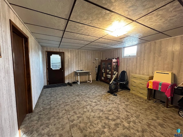 interior space featuring a paneled ceiling, carpet flooring, and wooden walls