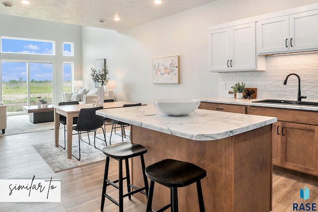 kitchen with white cabinetry, sink, a kitchen island, and light hardwood / wood-style floors