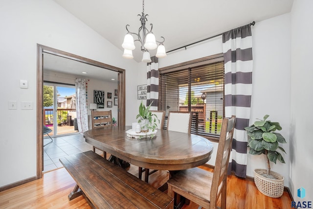 dining space featuring a wealth of natural light, light hardwood / wood-style flooring, lofted ceiling, and a notable chandelier