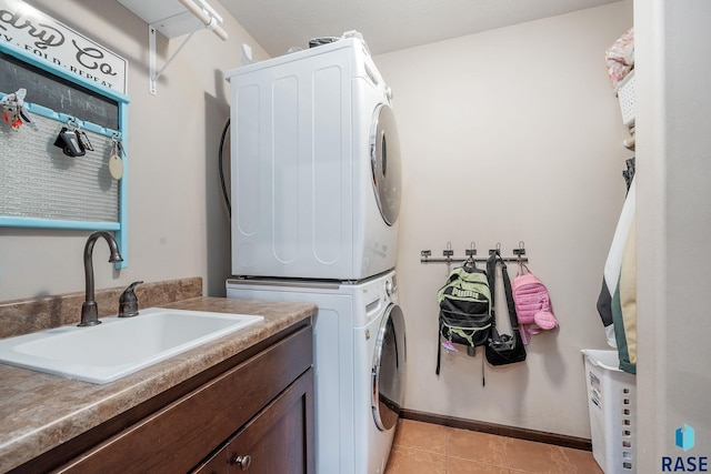 clothes washing area featuring cabinets, stacked washing maching and dryer, sink, and light tile patterned floors