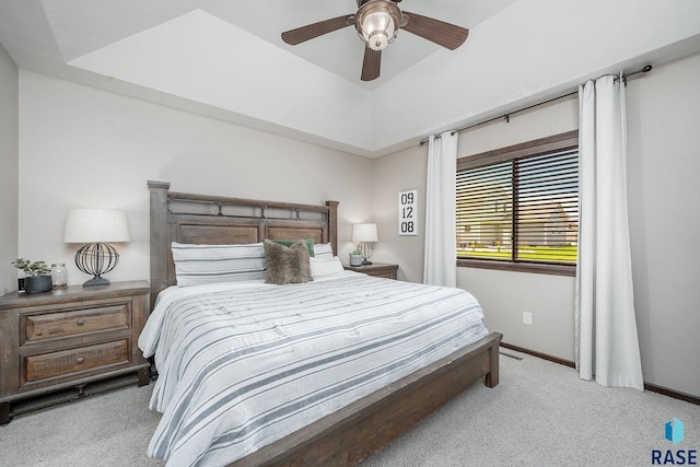 carpeted bedroom with a tray ceiling and ceiling fan