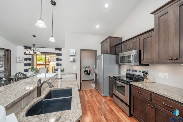 kitchen with light hardwood / wood-style floors, light stone countertops, appliances with stainless steel finishes, and vaulted ceiling