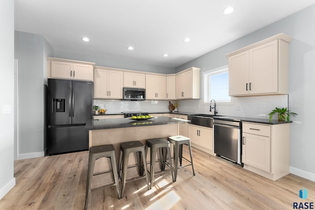 kitchen with a breakfast bar, stainless steel appliances, sink, light hardwood / wood-style flooring, and a kitchen island