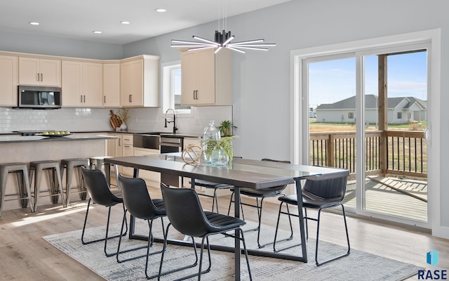 kitchen with backsplash, sink, light hardwood / wood-style floors, a kitchen bar, and a chandelier