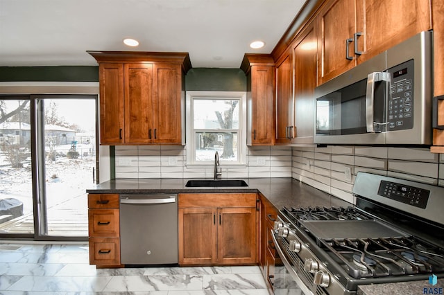 kitchen with tasteful backsplash, dark stone countertops, sink, and appliances with stainless steel finishes