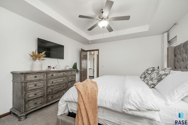 carpeted bedroom with ceiling fan and a raised ceiling