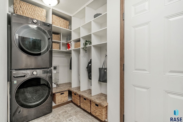 washroom with stacked washer / drying machine and light tile patterned floors