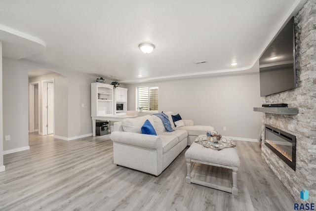 living room with a stone fireplace and light hardwood / wood-style floors