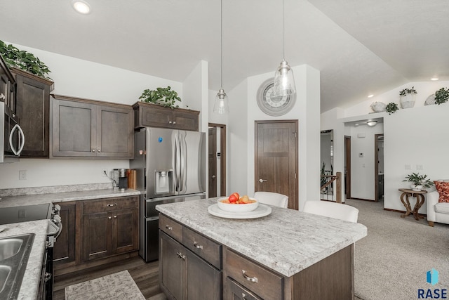 kitchen with pendant lighting, lofted ceiling, dark colored carpet, appliances with stainless steel finishes, and a kitchen island