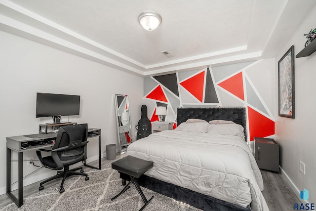 bedroom featuring wood-type flooring and a tray ceiling