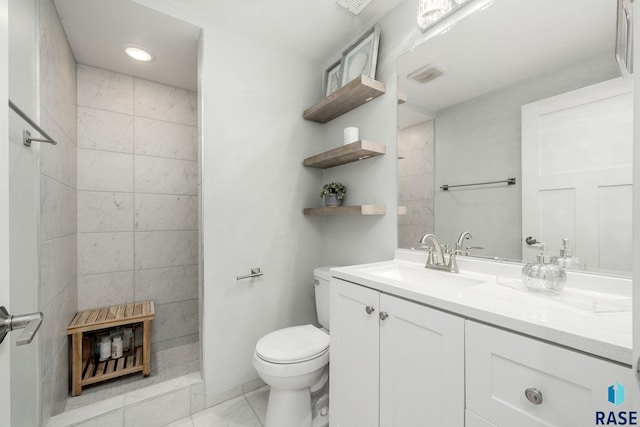 bathroom with a tile shower, vanity, and toilet