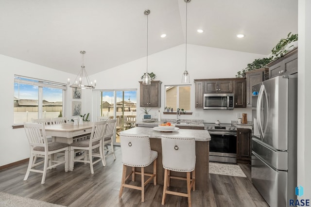 kitchen with stainless steel appliances, vaulted ceiling, a center island, dark hardwood / wood-style floors, and hanging light fixtures