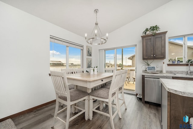 dining space featuring a notable chandelier, dark hardwood / wood-style floors, sink, and vaulted ceiling