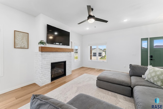 living room featuring a fireplace, light hardwood / wood-style flooring, and ceiling fan