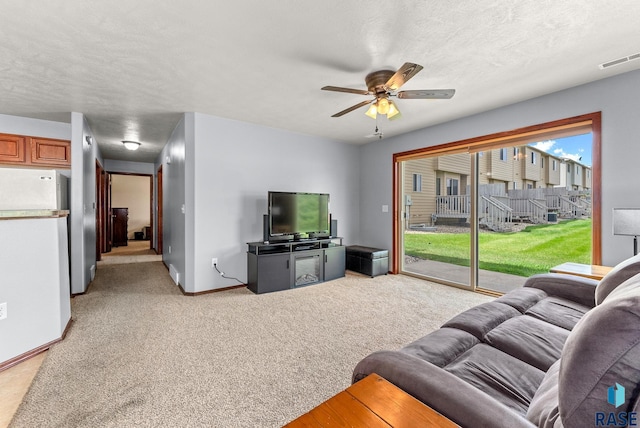 living room with a textured ceiling, ceiling fan, and light carpet