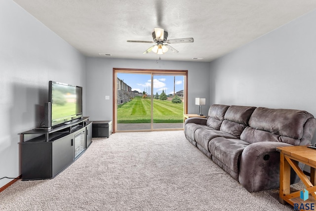 carpeted living room with ceiling fan and a textured ceiling