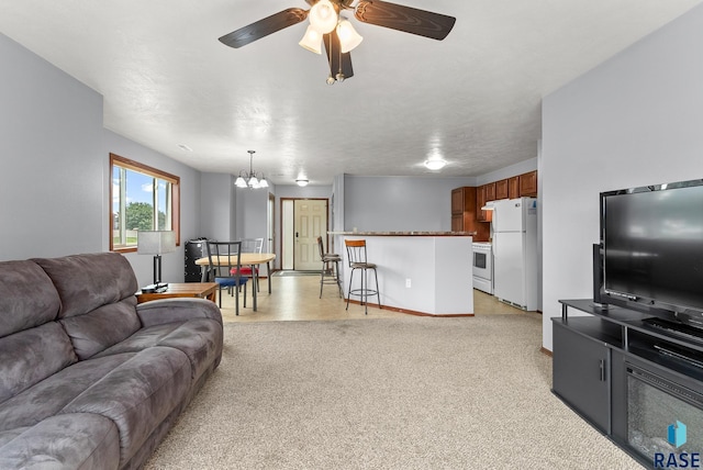 carpeted living room with ceiling fan with notable chandelier