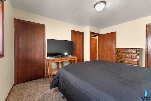 carpeted bedroom featuring a textured ceiling and two closets