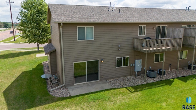 rear view of property with cooling unit, a balcony, a yard, and a patio