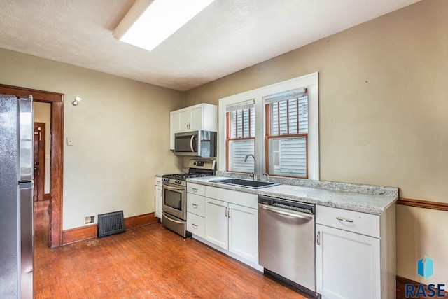 kitchen featuring dark hardwood / wood-style flooring, stainless steel appliances, white cabinetry, and sink