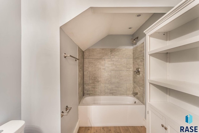 bathroom featuring tiled shower / bath combo, hardwood / wood-style flooring, and toilet