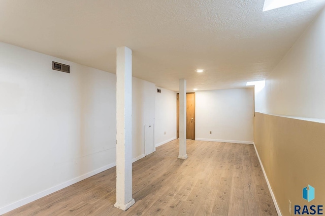 basement with a textured ceiling and light hardwood / wood-style floors