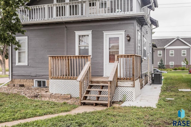 rear view of property featuring central AC unit, a balcony, and a yard