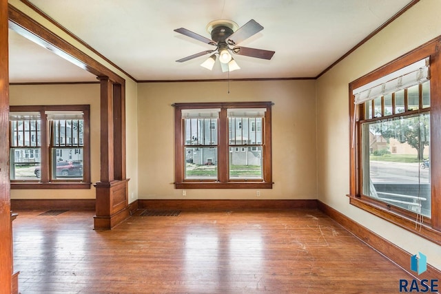 unfurnished room with hardwood / wood-style floors, ornate columns, ceiling fan, and crown molding