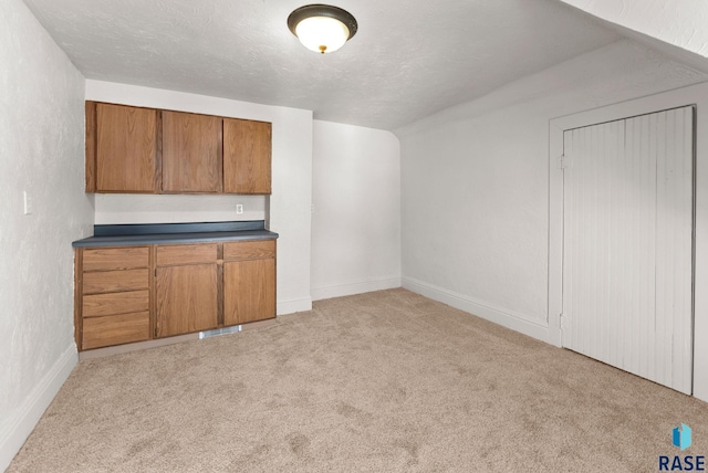 kitchen featuring light colored carpet and a textured ceiling