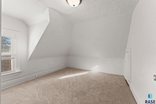 bonus room featuring lofted ceiling, carpet floors, and a textured ceiling