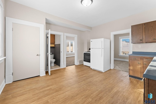 kitchen with light hardwood / wood-style flooring, a healthy amount of sunlight, and white appliances