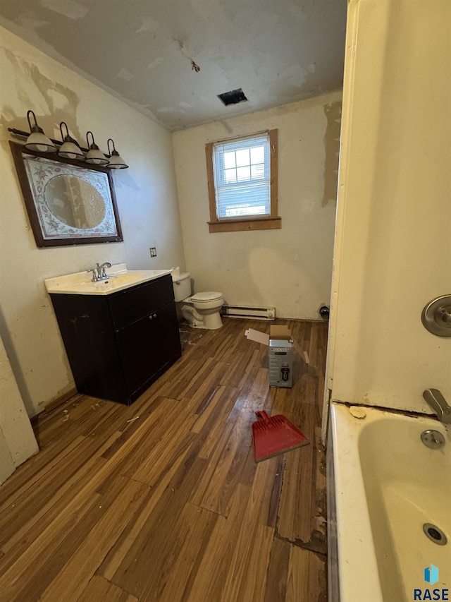 bathroom featuring a washtub, a baseboard radiator, wood-type flooring, toilet, and vanity